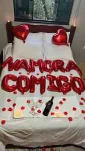 a bed covered in red hearts and wine glasses at Cabana Araucária in São Thomé das Letras