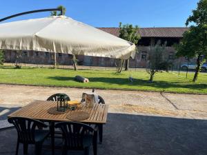una mesa de madera con 2 sillas y una sombrilla en Il cortile, en San Zenone al Lambro