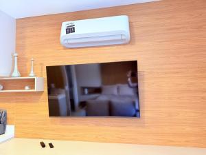 a television with a remote control on a wooden wall at Studio Prime - Vila Olímpia in Sao Paulo