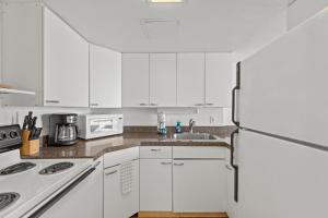 une cuisine avec des armoires blanches et un réfrigérateur dans l'établissement Ilikai Hotel 1801, à Honolulu