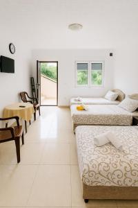 una camera con tre letti, un tavolo e una scrivania di Apartments Lejla a Dobra Voda