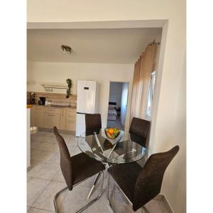 a glass table with black chairs and a kitchen at Apartmani Huno in Kampor +6 photos