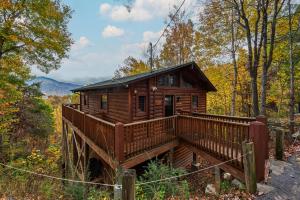 a cabin in the woods with a wooden deck at Mtn Views, Hot Tub, Sauna, EV, Arcade! in Gatlinburg