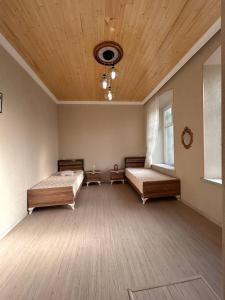 a bedroom with two beds and a wooden ceiling at Shaki Best house in Sheki