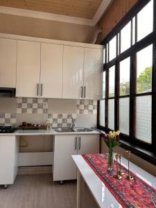a kitchen with white cabinets and a table with flowers on it at Shaki Best house in Sheki