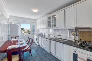 une cuisine avec des armoires blanches et une table à l'intérieur dans l'établissement Quarto duplo com vista rio num apartamento partilhado, à Bobadela