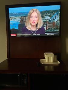 a television screen with a woman on it at Forestpark Suites in Cincinnati