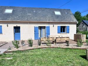 ein Haus mit blauen Türen und einer Holzbank in der Unterkunft Les gites Inclusifs d'OMAOMA in Saint-Jouin-Bruneval