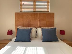 a bedroom with a large white bed with blue pillows at Calypso Beach Holiday House in Langebaan