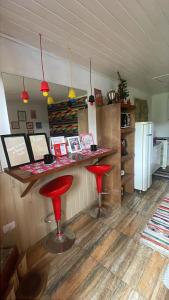 a bar with two red stools in a kitchen at Chale Sabrina in Campos do Jordão