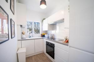 a white kitchen with a sink and a stove at Larkhall Retreat- Village Centre, Parking, 4K TVs, 10mins To City Centre in Bath