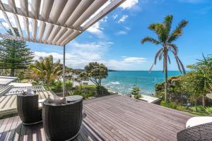 Una terraza al aire libre con sillas y vista al océano. en Takapuna Clifftop with Pool and Hot Tub, en Auckland