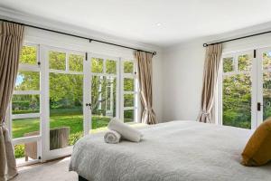 ein Schlafzimmer mit großem Bett und großen Fenstern in der Unterkunft Norfolk House, Luxury Villa With Spa and Lake Views in Taupo + 38 Fotos