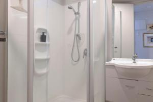 a white bathroom with a shower and a sink at Lakeview Retreat With Private Geothermal Pool in Taupo +24 photos