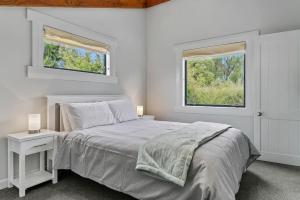 una camera da letto bianca con un letto e due finestre di Central and Cozy 2BR Retreat With Parking and Free Wifi a Taupo