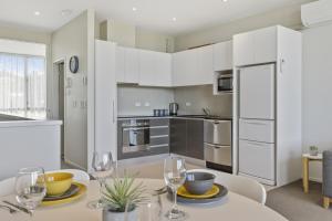 a kitchen with white cabinets and a table with wine glasses at Water Views Apartment With Pool and Lake Access in Taupo