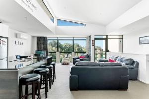 una sala de estar con 2 sofás y un bar en Luxury Riverfront Apartment With Views and Pool Access, en Taupo