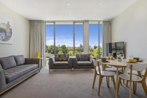 a living room with a couch and a table and chairs at Water Views Apartment With Pool and Lake Access in Taupo