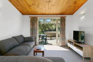 ein Wohnzimmer mit Sofa und Fernseher in der Unterkunft Bellbird Cottage With Lake and Mountain Views in Taupo