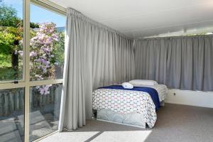 ein Schlafzimmer mit einem Bett und einem großen Fenster in der Unterkunft Bellbird Cottage With Lake and Mountain Views in Taupo