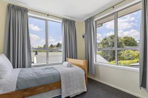 a bedroom with a bed and two windows with a view at Fantail Retreat, Family 4BR Near Lake and Gardens in Taupo