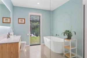 a bathroom with a tub and a toilet and a sink at Peaceful Luxury Retreat with Lake Views and Spa Pool in Taupo +29 photos