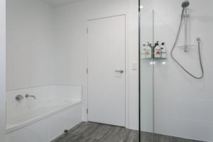 baño blanco con ducha y puerta de cristal en Unwind on Wai, New 4BR Home With Style and Comfort, en Taupo 26 fotos más