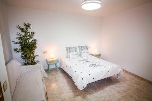 a bedroom with a white bed with two tables and a plant at Casa Menta in Bañeres de Mariola