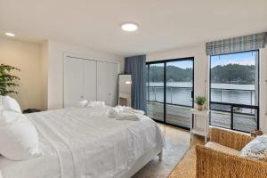 KamilcheにあるLakefront Luxury Stunning Views Dock Hot Tubの大きなベッドと大きな窓のある寝室