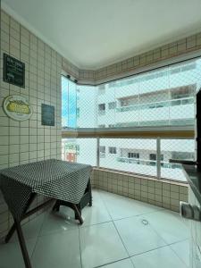 une pièce avec une table et une grande fenêtre dans l'établissement Cantinho do Churrasco - Varanda Gourmet a 60 mts praia, à Praia Grande