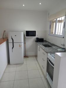 a white kitchen with a refrigerator and a stove at Departamentos Capernaum in Santa Rosa