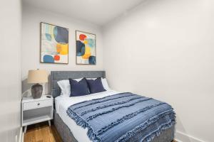 een witte slaapkamer met een bed met een blauwe deken bij Prime NYC Location 4BR Spacious Haven in New York