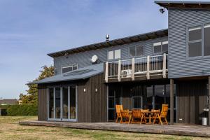 a house with a deck and a table and chairs at Wanaka Retreat Spa, Sauna & Mountain Views in Wanaka