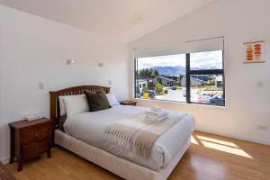 a bedroom with a bed and a large window at Wanaka Retreat Spa, Sauna & Mountain Views in Wanaka