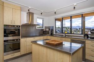 a kitchen with wooden cabinets and stainless steel appliances at Wanaka Retreat Spa, Sauna & Mountain Views in Wanaka