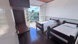 a small room with two beds and a window at Casa Campos do Jordão in Campos do Jordão