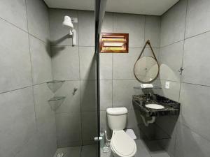 a bathroom with a shower and a toilet and a sink at Chalé Refúgio dos Corais in Japaratinga