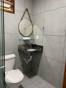 un bagno con un water, un lavandino e uno specchio di Chalé Refúgio dos Corais 1 a Japaratinga
