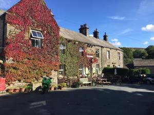 a building covered in ivy with a motorcycle in front of it at The Clarendon Country Pub with rooms in Grassington