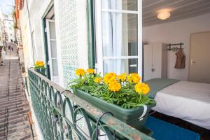 una caja de ventanas con flores amarillas en el balcón en Lisbon Inn Bica Suites, en Lisboa