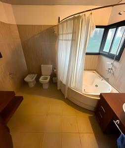 a bathroom with a tub and a toilet and a sink at Hermosa Mansión c/pileta y jacuzzi -Barrio privado in Bajo Lunlunta
