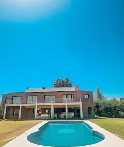 an exterior view of a house with a swimming pool at Hermosa Mansión c/pileta y jacuzzi -Barrio privado in Bajo Lunlunta