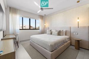 ヌエボ・バジャルタにあるPuertArena Nuevo Nayarit - Modern Comfort Near the Beachのベッドと机と窓のある寝室