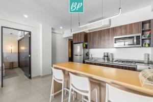ヌエボ・バジャルタにあるPuertArena Nuevo Nayarit - Modern Comfort Near the Beachのキッチン(木製カウンタートップ、白い椅子付)