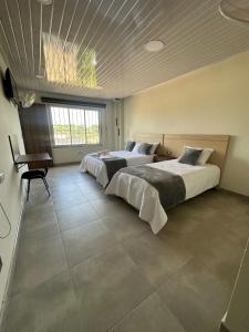 a bedroom with two beds and a table in it at Hotel Diamante Sarare 2 in Saravena