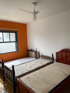 two beds in a room with orange walls at Casa com piscina e churrasqueira Itanhaém in Itanhaém