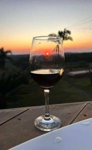a glass of wine sitting on a table with the sunset at Beleza de Angra Apartamento Aconchegante in Angra dos Reis