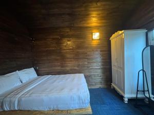 a bedroom with a bed and a wooden wall at Nhà Của Sen in Da Thien