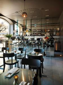 a restaurant with tables and chairs and a bar at Nobis Hotel Stockholm, a Member of Design Hotels™ in Stockholm