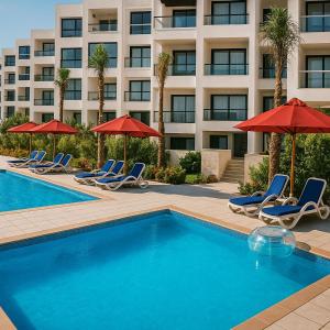 塞得港Unwind in style at Porto Said Chalets by the sea的一个带椅子和遮阳伞的游泳池以及酒店 更多81张照片